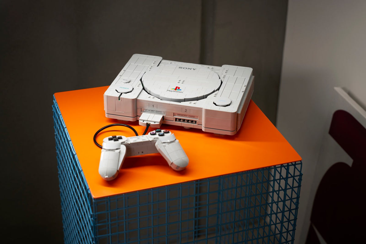 The brick-built original PlayStation console and controller displayed beside a television and game cases